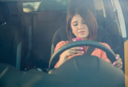 distracted driver in Ontario looking at her phone while stopped at red light