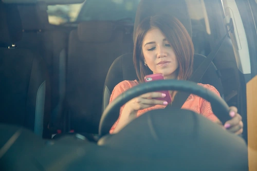 distracted driver in Ontario looking at her phone while stopped at red light